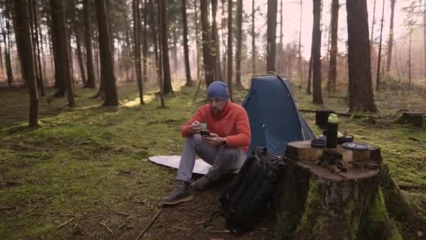 Утром Кемпинге Осеннем Лесу Турсит Просматривает Интернет Своем Смартфоне Сидя — стоковое видео