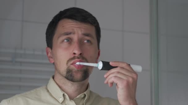 Sabah Banyoda Dişlerini Elektrikli Diş Fırçasıyla Temizleyen Tişörtlü Bir Adam — Stok video