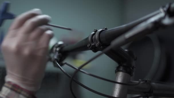 マウンテンバイクハンドルバーの自転車整備士は サイクリングストア内の特別な機器を使用してネジを外します サービスステーションで自転車を提供しています 自転車のテーマ販売と修理 — ストック動画
