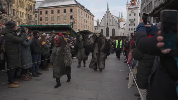 2022年12月11日 ミュンヘンだ ドイツだ マリエンプラッツ クランプスラウフ ウーバー マンシュナー クリスキンルマルクト クリスマス前のクランプス祭のパレードでミュンヘンの中央広場のクランプスマスクの人々 — ストック動画