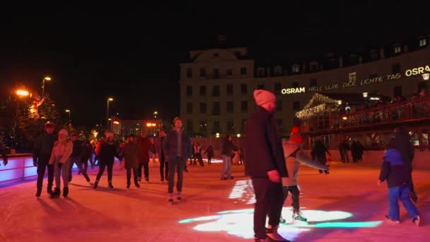 2022年12月5日 ドイツだ ミュンヘンだ ミュンヘンのカールスプラッツで人々のアイススケート ライフスタイルと休日 ヴァインヒャクスマート 夕方にミュンヘンのダウンタウンのクリスマスマーケットでアイススケートリンク — ストック動画