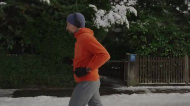 Ülke genelinde koşan kulaklıklı bir sporcu kışın Almanya 'da parktaki patikaları karla kapladı. Koşucu kış günlerinde Avrupa kırsalında koşarken müzik dinler. Karda koş. 