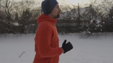 Ülke genelinde koşan kulaklıklı bir sporcu kışın Almanya 'da parktaki patikaları karla kapladı. Koşucu kış günlerinde Avrupa kırsalında koşarken müzik dinler. Karda koş. 