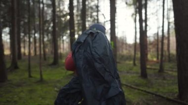 Tourist makes camp in woods, sets up tent in meadow in fall forest, prepares for an overnight stay in campsite. Backpacker builds tent on solo autumn trip in forest. Hiking and staying in nature. 