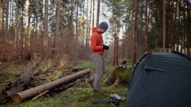 Man hiker sets up camping tent in the fall forest on backpacking expedition. Traveler setting an overnight tent in the wilderness in the fall. Theme of tourism and trekking. Outdoor weekend activity. 