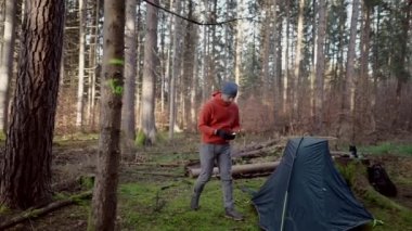 Camping, tourism and travel concept. Man setting up tent outdoors. Hiker assembles campsite tent in the autumnal forest. Traveler installing tent in autumn woods. Outdoor weekend Activity. 