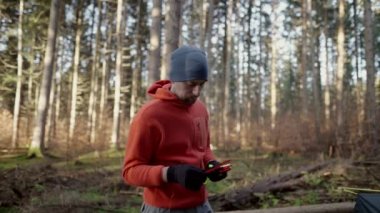 Tourist makes camp in woods, sets up tent in meadow in fall forest, prepares for an overnight stay in campsite. Backpacker builds tent on solo autumn trip in forest. Hiking and staying in nature. 