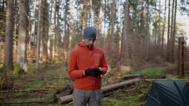 Camping, tourism and travel concept. Man setting up tent outdoors. Hiker assembles campsite tent in the autumnal forest. Traveler installing tent in autumn woods. Outdoor weekend Activity. 