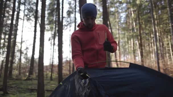 キャンプ 旅行のコンセプト 男はテントを屋外に設置 ハイカーは 秋の森の中でキャンプ場のテントを組み立てます 秋の森にテントを設置する旅行者 週末野外活動 — ストック動画