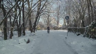 Male cyclist arrived at home on bicycle in winter weather on slippery path through park and going about parking bike in garage in family home in Germany. Outdoor activities in cold season. 