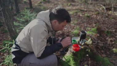 Outdoor walker takes cooked fast food from a gas stove in the forest during a fall camping trip. Traveler eats sublimated meals while hiking out of travel gear. Hiker eating oatmeal while backpacking