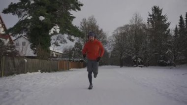 Male jogger running on a slippery snow surface in a park in winter in loose footwear in winter. Wrong sneakers for running in snowy weather. Workout safety. Training outside in cold snowy weather. 