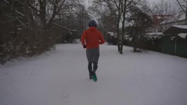 Topic of the right equipment and footwear for winter training outdoors. Runner slides on slippery snowy surface while jogging outside in winter. Sneakers slipping while running. Sleazy road. 