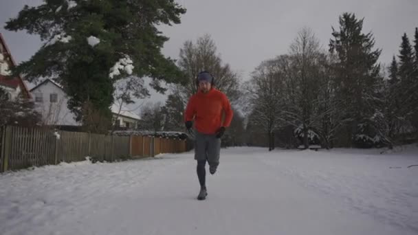冬は緩んだ履物で冬の公園の滑りやすい雪の表面で走る男性のジョギング 雪の天気で走るための間違ったスニーカー 安全装置を使え 寒い雪の中外での訓練 — ストック動画