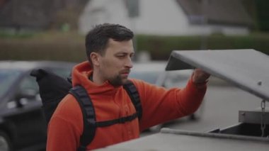 Man throws trash in clear garbage bag with biologicals food waste into garbage can near home before go to work in Europe. Garbage sorting. Containers for waste separation. Environmental conservation. 