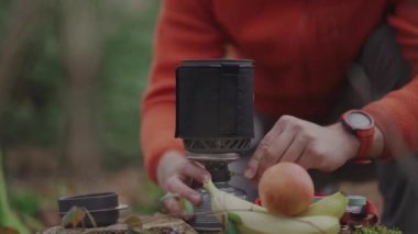 Caucasian male backpacker fires up piezo lighter for boiling water in camping. Tourist sparking gas stove during campsite lunch. Hiking, camping equipment. Cooking system ignition type. push button