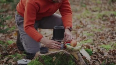 Caucasian male backpacker fires up piezo lighter for boiling water in camping. Tourist sparking gas stove during campsite lunch. Hiking, camping equipment. Cooking system ignition type. push button
