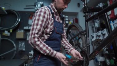 Bike repairman unscrews the bottom bracket of the front crankset with a specialized tool in workshop. Maintenance and service concept. Bicycle crank set. Remove a part of the vehicle for service. 