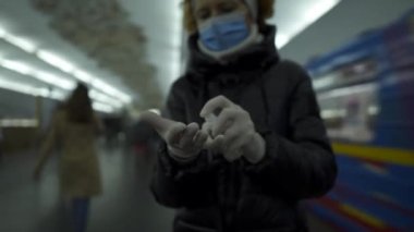 Individual disinfection during city trips transport, protection viruses and bacteria using medical mask and gloves. Older Caucasian woman fulfills safety requirements during coronavirus epidemic.