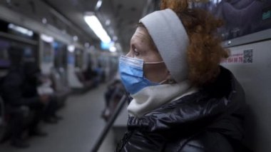Mature woman in medical protective mask traveling in subway train. Concept of new life reality during COVID 19 pandemic. Pandemic travel. Senior woman in face mask in public transport. Virus outbreak.