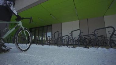 Man cyclist locks bicycle in a street parking lot in Europe in winter snowy weather. Locking bike for parking . Protecting your cycle from burglary. Commuting on a bicycle in the frost. 