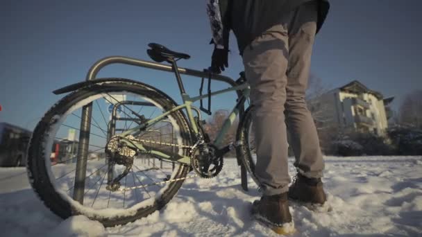 男性サイクリストは 雪の多い ドイツの寒い冬の天気の通りの駐車場で駐車自転車のロックを解除します サイクルロックを開く 自転車が盗まれないように保護する 男は外のラックで自転車のロックを解除 — ストック動画