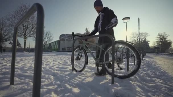 Cyclist Attaches Bicycle Lock Street Parking Germany Winter Sunny Snowy — Stok video