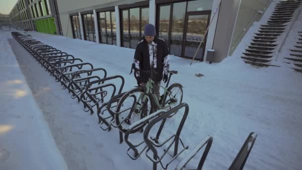 Male Cyclist Unlocks Parked Bicycle Street Parking Lot Snowy Freezing — Stock video