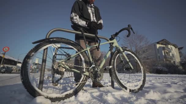 自転車用のセキュリティと盗難防止ロック 男のサイクリストは ドイツのヨーロッパの都市で屋外の自転車駐車場でサイクルのロックを解除します 男ロック解除自転車でオープンラックで冬に雪の天気 — ストック動画