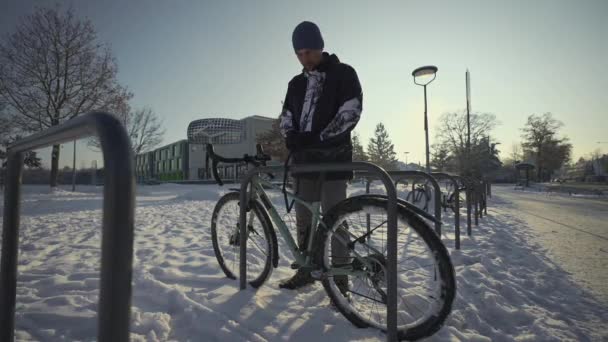 Male Cyclist Unlocks Parked Bicycle Street Parking Lot Snowy Freezing — 비디오
