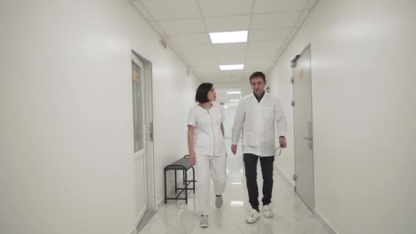 Two Doctors Man Woman Walk Quickly Hospital Corridor Discuss Mri — 图库视频影像