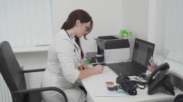 Confident Female General Practitioner Takes Notes Medical Report Book Sitting — 图库视频影像