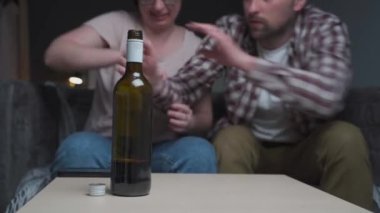 Male and female alcohol addicts fight over a bottle of wine at home. The topic of drunkenness and domestic violence battles. Crisis in family relationships alcoholism addiction and bad habits concept