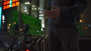 Subject of hand disinfection after visiting public places. Man cyclist sprays alcoholic sanitizer on his hands after shopping in a store, puts on his helmet and leaves, in the evening in the city. 