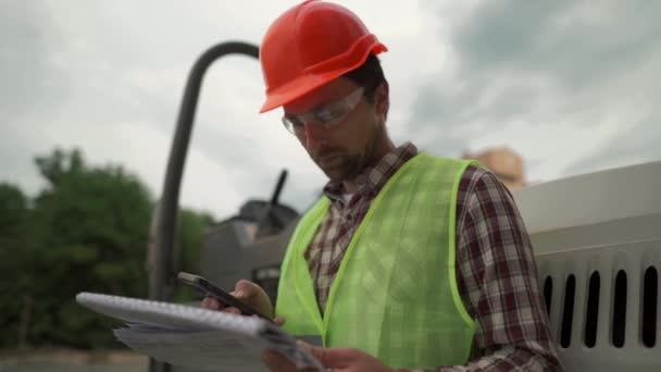 Μηχανικός Οικοδόμος Hard Hat Στέκεται Ενάντια Paver Στο Εργοτάξιο Τον — Αρχείο Βίντεο