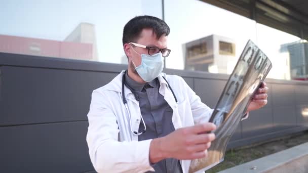 男性医師はCtスキャンフィルムで胸部のX線を検査します Covid 19における体内X線検査の検出 コロナウイルス流行のMriスキャンの概念普及 テーマ肺放射線撮影 — ストック動画