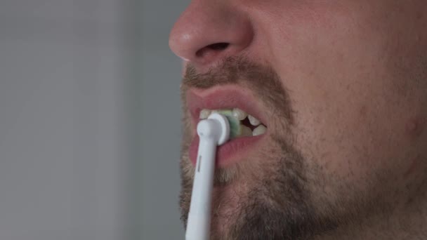 現代的な電動歯ブラシで歯をブラッシングし 白くするというテーマ 超音波歯科ブラシで彼の歯をきれいに男のクローズアップ 朝のルーチン 口腔衛生 歯ブラシの振動 — ストック動画