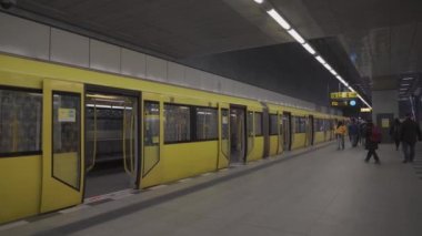 10 Mart 2022, Almanya, Berlin. Modern sarı metro treni ve Berlin 'deki yolcular. Berlins metropolitan demiryolu sistemi. Güncellenmiş vagonlar ve banliyö yolcuları. Almanya 'da yeraltı toplu taşımacılığı