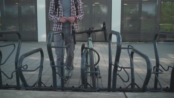 自行车防盗 自行车街停放自行车 骑自行车的人打开自行车锁 骑自行车离开 外面有人把自行车开锁在车架上 安全和防盗锁 — 图库视频影像