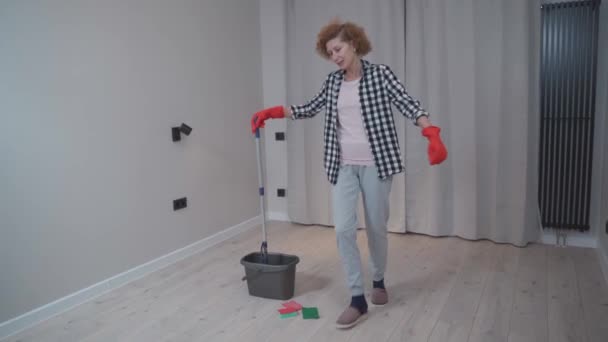 Χαρούμενη Ώριμη Γυναίκα Που Καθαρίζει Ένα Νέο Διαμέρισμα Χωρίς Έπιπλα — Αρχείο Βίντεο