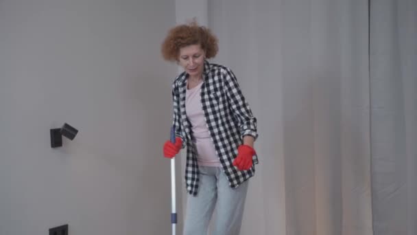 Starsza Kobieta Sprząta Przed Wprowadzeniem Się Nowego Mieszkania Tańcząc Śpiewając — Wideo stockowe