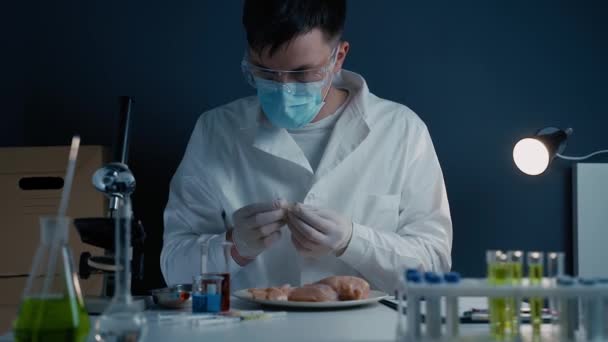 研究室で反応を待っている培養肉に赤い液体を滴下科学者 微生物学者は化学ビーカーから色のついた液体を分注して肉のサンプルを調べる実験室のピペットを使う — ストック動画