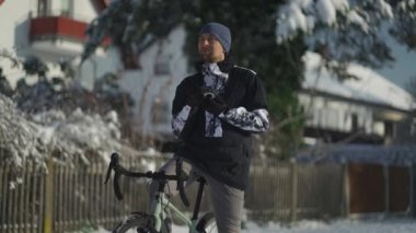 Cyclist uses smartphone to find road, building route on map, navigation in winter in snowy, sunny weather in Germany. People, sports, active lifestyle and modern technology. GPS navigation on phone. 