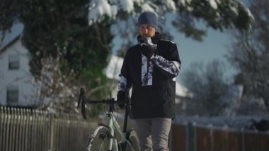 Man on bicycle ride in winter in freezing snowy weather stopped and used a mobile phone, using app to find GPS positioning, route guidance, online map and navigation while biking. Concept of journey. 