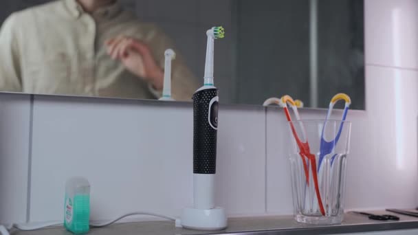 Αφαιρεί Την Ηλεκτρική Οδοντόβουρτσα Από Φόρτιση Και Βουρτσίζει Δόντια Πριν — Αρχείο Βίντεο