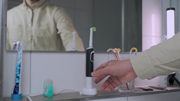 Man Verwijdert Elektrische Tandenborstel Van Lading Poetst Tanden Voor Het — Stockvideo