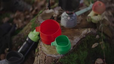 Kamp yaparken çay yapan yürüyüşçü, sonbaharda ormanda ocakta su kaynatan adam. Yemek pişirmek ve sıcak içecekler için kamp malzemeleri. Gezgin, gazı pişirmek için sistemi kullanarak çay hazırlar.. 
