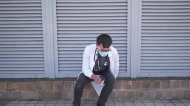 Yorgun genç doktor hastane dışında çalışırken maskesini çıkarıp dinlenmeye ve kahve içmeye geliyor. Doktor vardiyadan sonra dinleniyor. Dışarıdaki klinikten kahve içiyor.. 