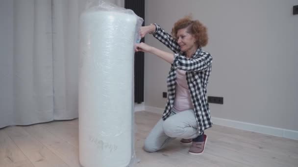 Dojrzała Kobieta Rozpakowuje Nowy Materac Podczas Przeprowadzki Nowego Mieszkania Szczęśliwa — Wideo stockowe