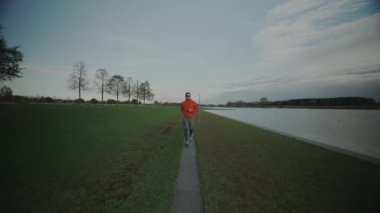 Almanya, Münih ve Almanya 'da sonbaharda parkta yürüyüş yolu boyunca koşan sporcu bir adam. Sonbaharda bir göletin yanında koşan bir erkek. Suyun yanında açık hava egzersizi. İnsanlar ve spor konsepti. 